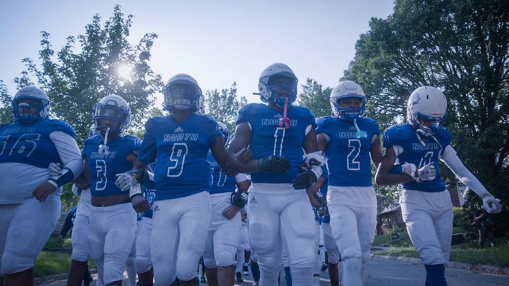 North High Polars players in uniform walk to the field for a football game
