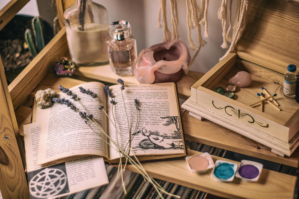 Mythic storytelling and ritual tools — book, crystals, candle, lavender — connecting ancient stories to secular spirituality.