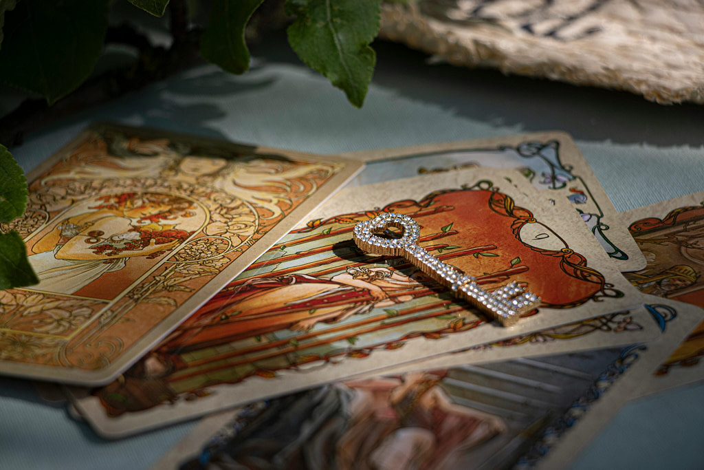 Tarot cards arranged in soft natural light with a jeweled key resting on top, symbolizing guidance, intuition, and crossing a life threshold.