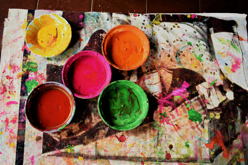 Vibrant paint bowls on a splattered canvas representing creative inspiration for the new moon in Gemini