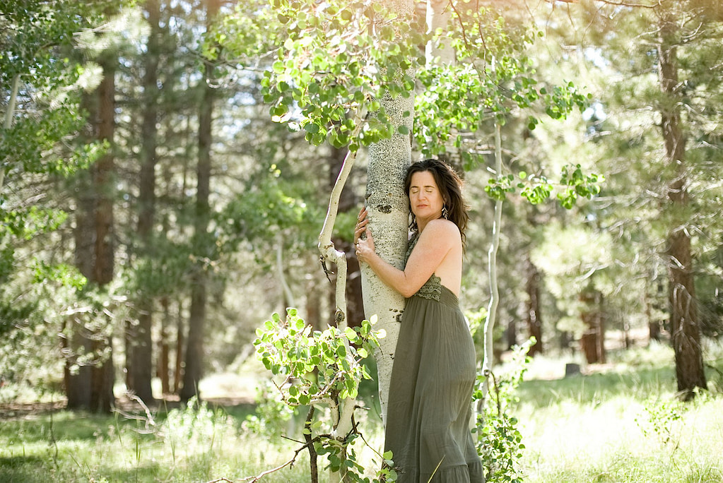Woman in nature, hugging a tree, meditating on the goddess. Modern artistic representation of goddess archetypes as symbols of wisdom, strength, connection, and the collective unconscious.