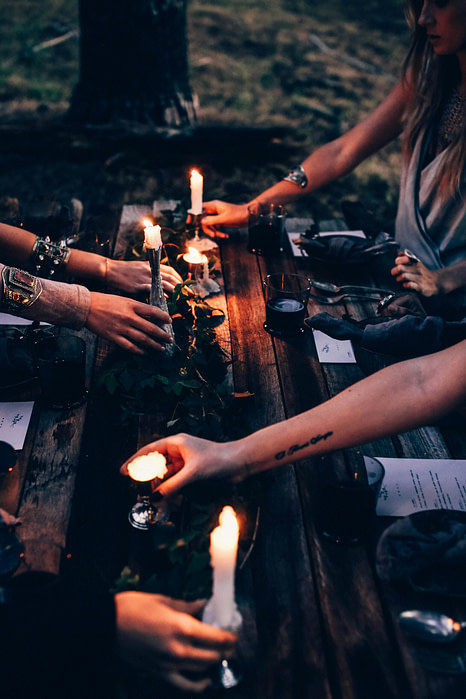 Women lighting candles around a wooden table during an intimate ritual gathering
